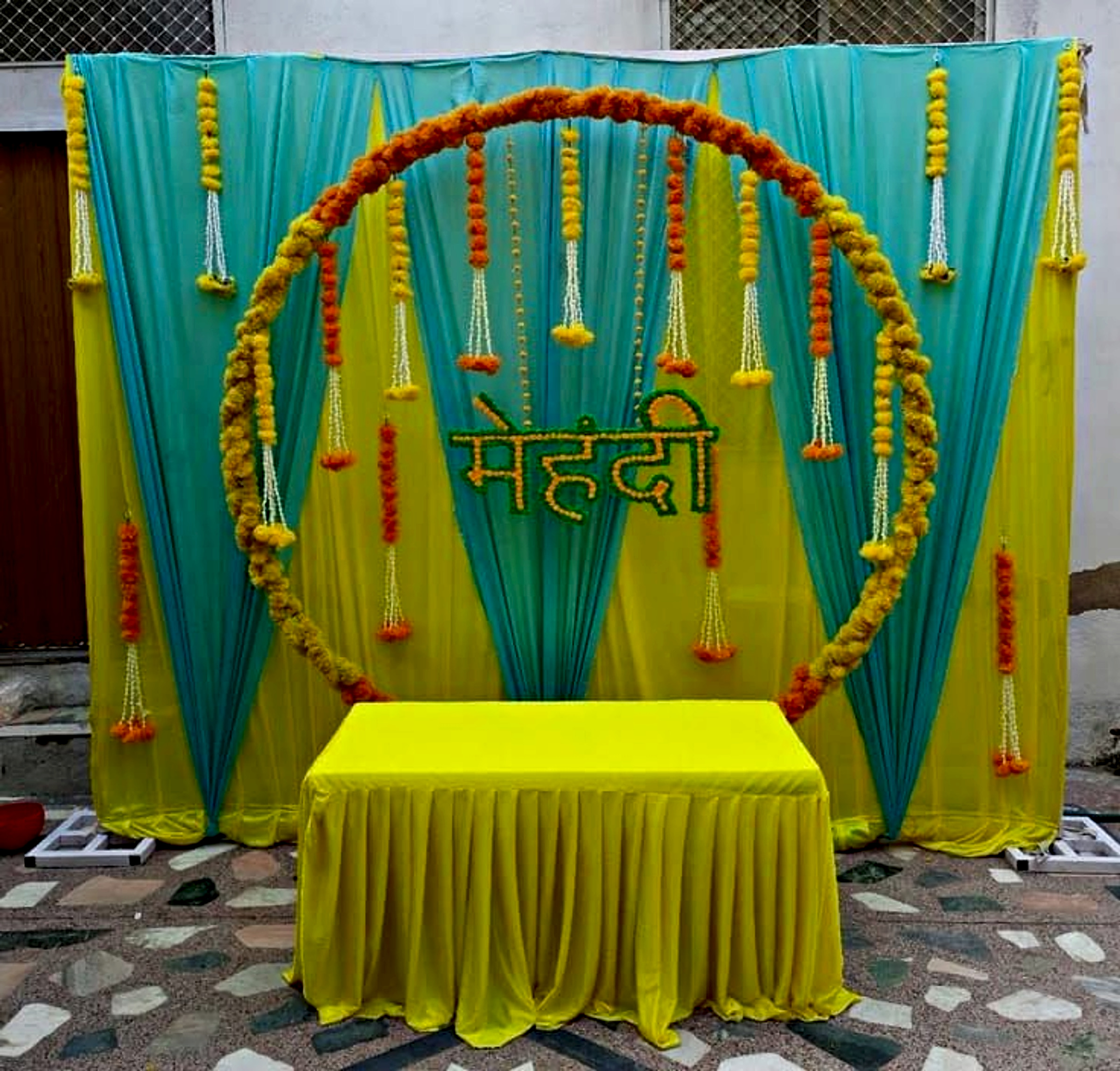 Traditional Mehndi Event Decor In Yellow And Turquoise With Floral Ring Backdrop - wedding decoration by ARV Decor